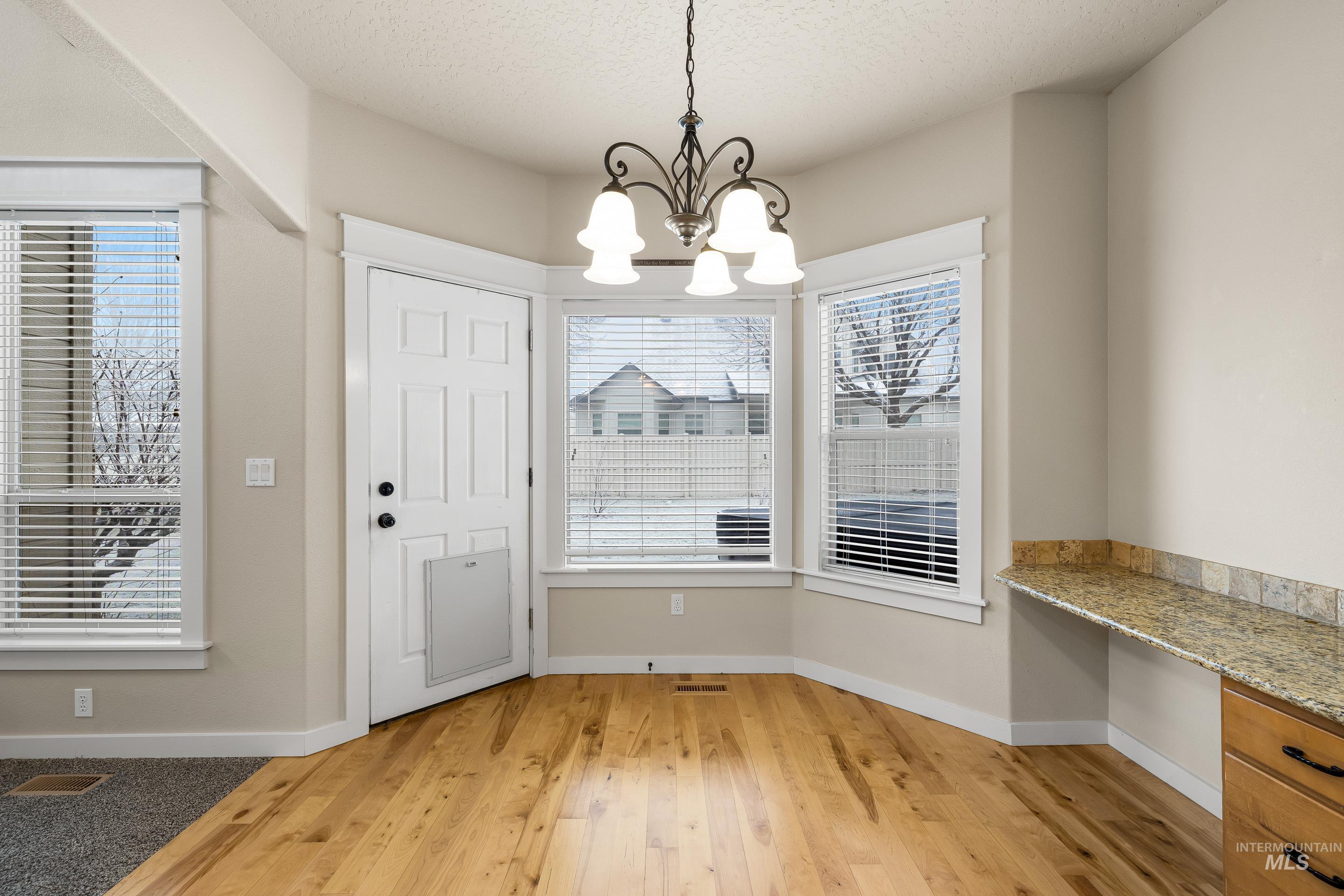2578 South Groom Way Meridian, ID 83642 - Photo 8 of 39 Unfurnished dining area with built in study area, light wood-type flooring, a chandelier, and a textured ceiling