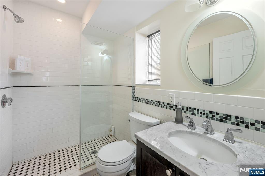 682 Greeley Avenue, Unit A Fairview, NJ 07022 - Photo 22 of 23 a bathroom with a granite countertop sink a toilet and a mirror