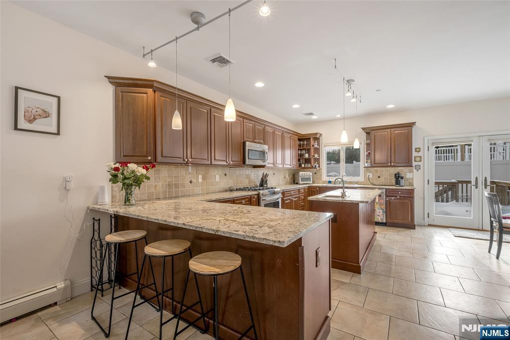682 Greeley Avenue, Unit A Fairview, NJ 07022 - Photo 7 of 23 a kitchen with a table chairs microwave and cabinets