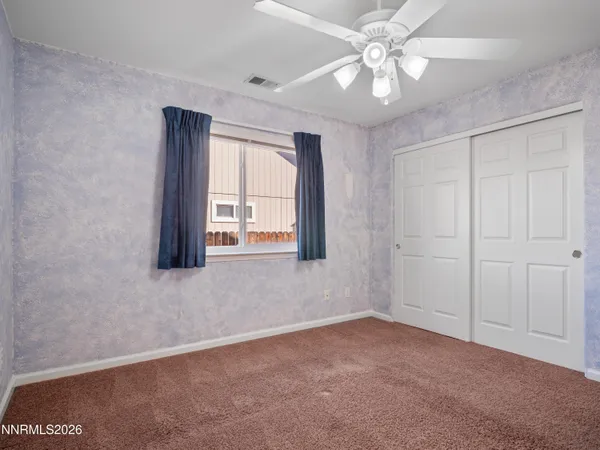 an empty room with windows and ceiling fan