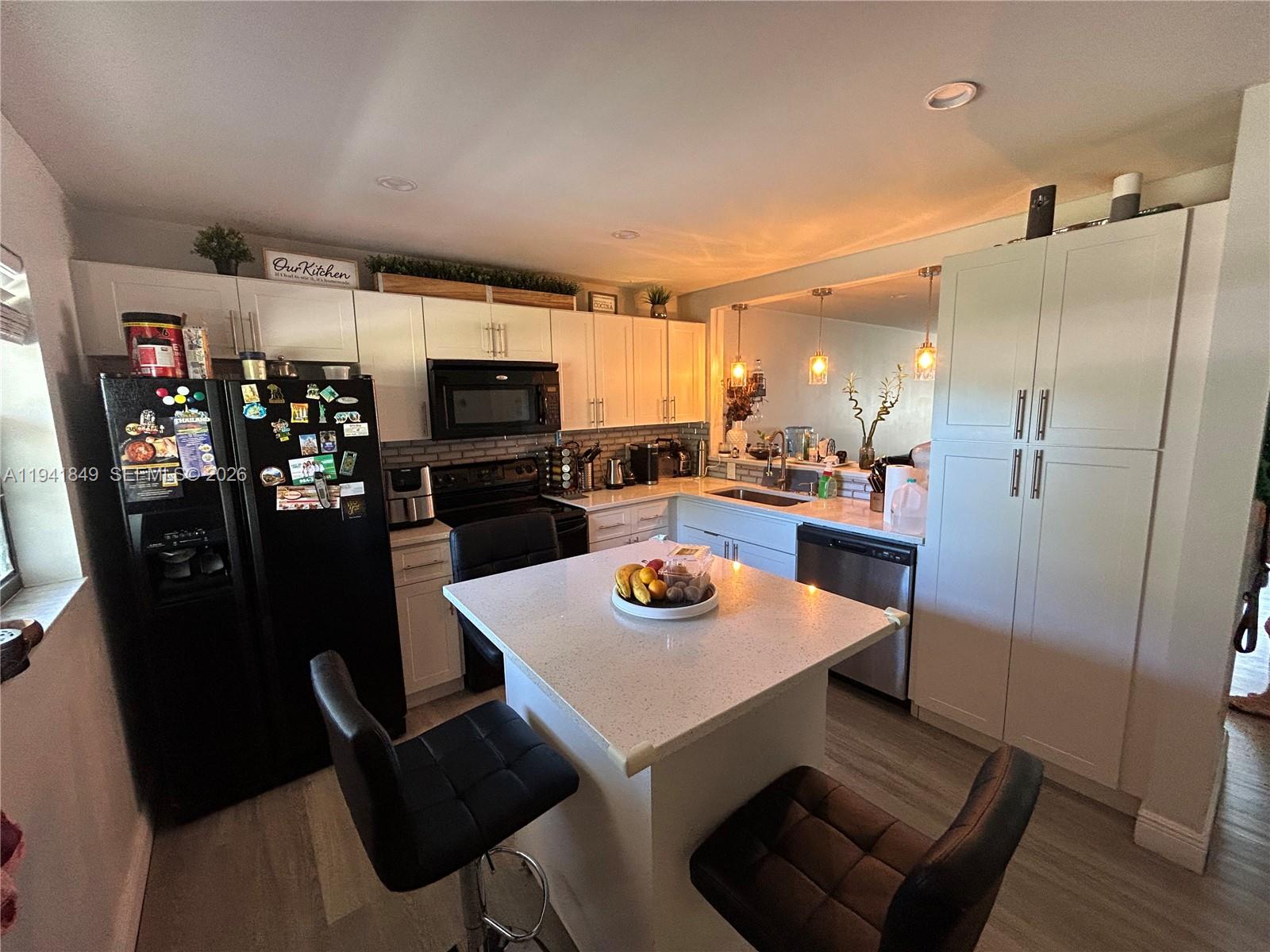 200 Gate Road, Unit 207 Hollywood, FL 33024 - Photo 8 of 38 a kitchen with a refrigerator a stove top oven a sink and a dining table with wooden floor