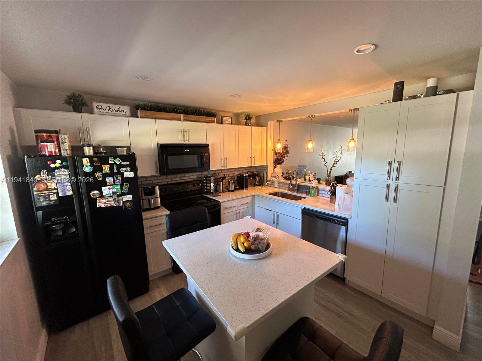 200 Gate Road, Unit 207 Hollywood, FL 33024 - Photo 9 of 38 a kitchen with stainless steel appliances a refrigerator a stove a microwave oven a dining table and chairs