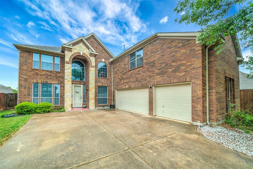 Traditional-style home featuring brick siding, a garage, and concrete driveway