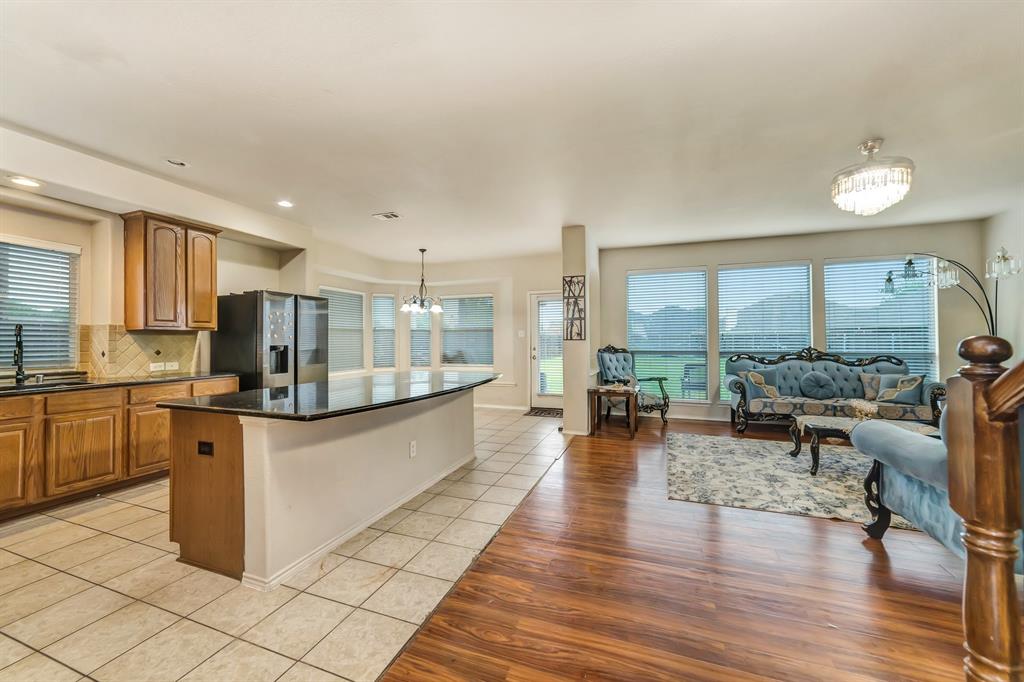 2312 Tawny Owl Road Grand Prairie, TX 75052 - Photo 40 of 40 Kitchen featuring a chandelier, wood finish cabinetry, open floor plan, a center island, and stainless steel fridge