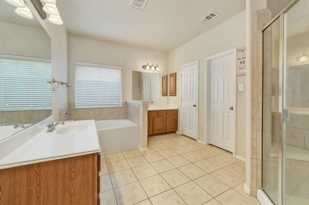 2312 Tawny Owl Road Grand Prairie, TX 75052 - Photo 21 of 40 Bathroom with two vanities, a shower stall, light tile patterned floors, and a garden tub