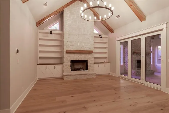 a view of an empty room with a fireplace and wooden floor