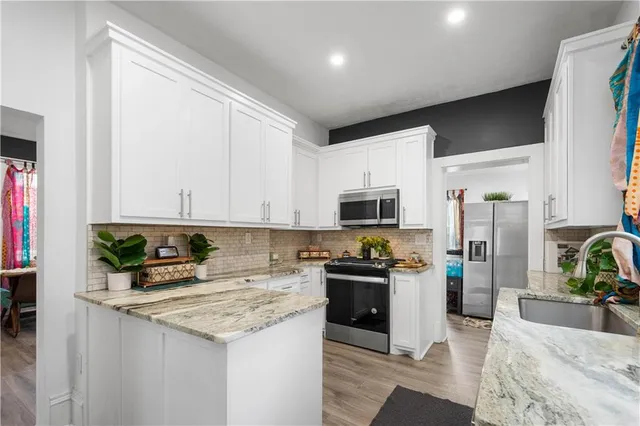 a kitchen with stainless steel appliances granite countertop a stove top oven a refrigerator a sink and dishwasher with wooden floor