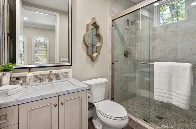 a bathroom with a granite countertop sink a toilet and shower
