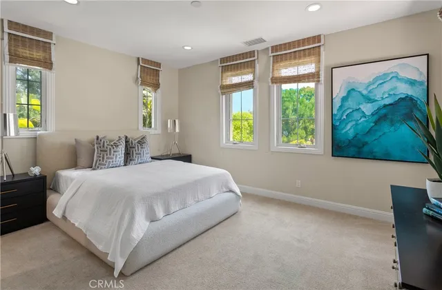 a bedroom with a bed painting and a large window