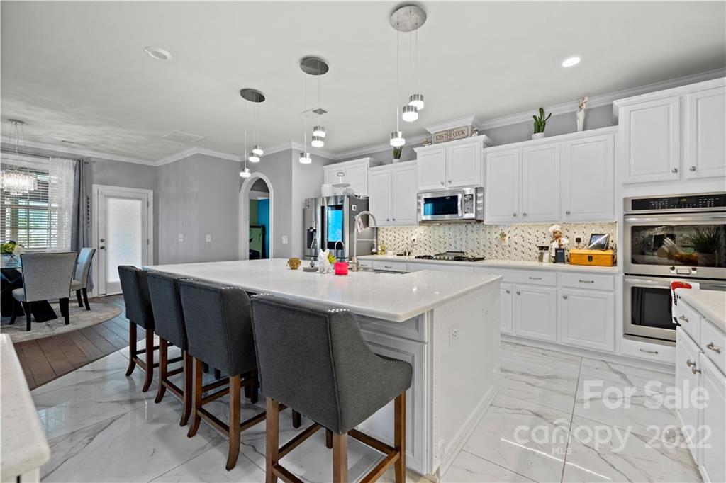 1908 Chatooka Lane Waxhaw, NC 28173 - Photo 14 of 47 a kitchen with stainless steel appliances kitchen island granite countertop a table chairs sink and cabinets