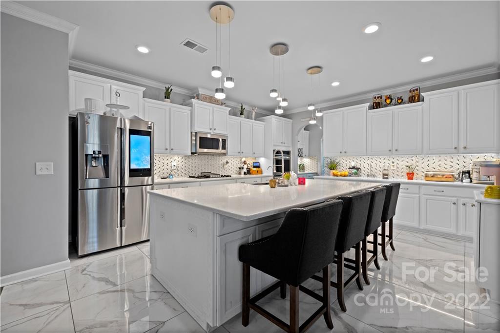 1908 Chatooka Lane Waxhaw, NC 28173 - Photo 17 of 47 a kitchen with stainless steel appliances kitchen island granite countertop a refrigerator a stove a sink a dining table and chairs