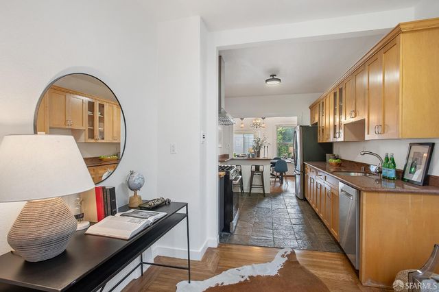 a kitchen with stainless steel appliances granite countertop a stove top oven a sink a dining table and chairs with wooden floor