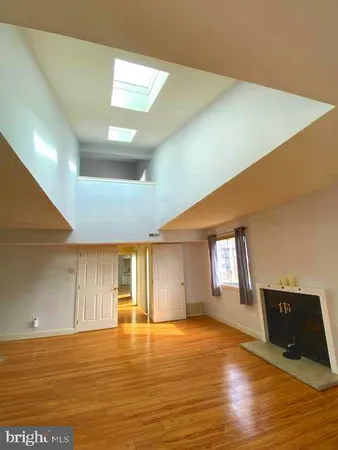 a view of an empty room with window and wooden floor
