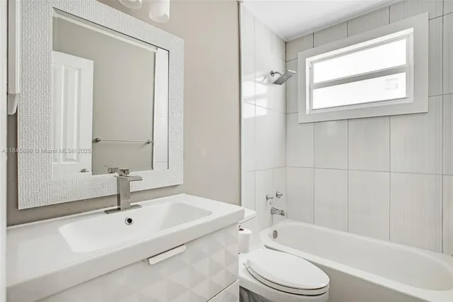 a bathroom with a bathtub shower sink vanity mirror and toilet