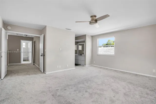 an empty room with ceiling fan and windows
