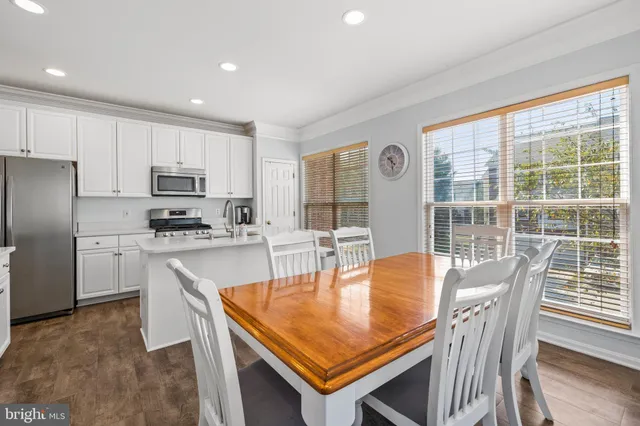 a kitchen with stainless steel appliances granite countertop a stove a refrigerator a sink a dining table and chairs