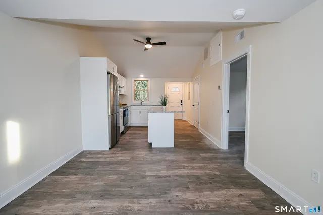 a view of a kitchen with refrigerator and wooden floor