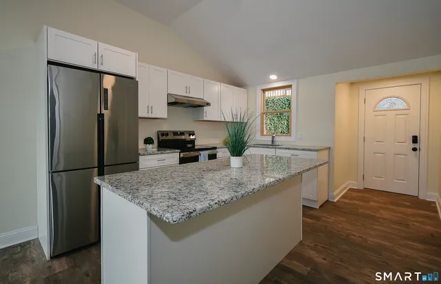 a kitchen with stainless steel appliances granite countertop a refrigerator a stove and a sink