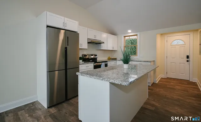 a kitchen with stainless steel appliances granite countertop a refrigerator a stove and a sink