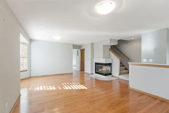 an empty room with wooden floor fireplace and windows