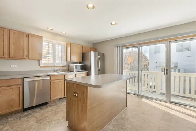 a large kitchen with kitchen island a large window a sink and cabinets