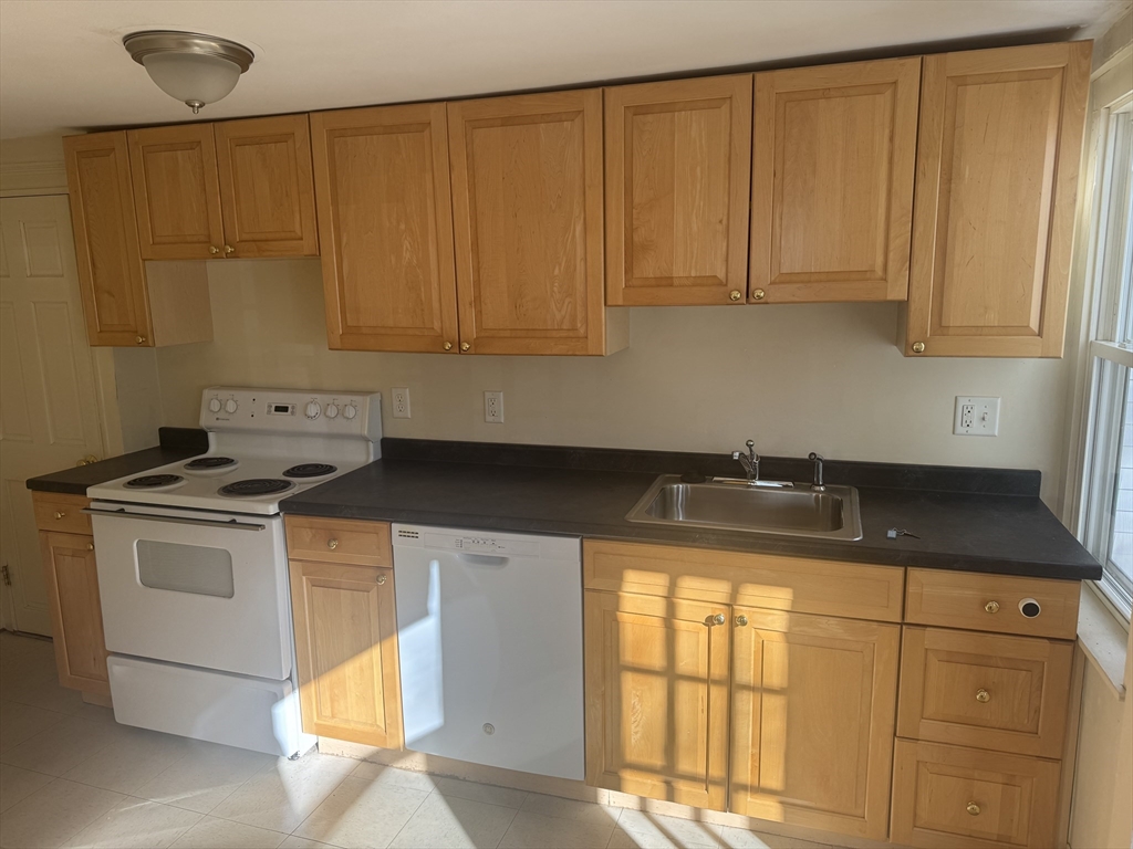 5 Curve Street, Unit 1 Lexington, MA 02420 - Photo 3 of 10 a kitchen with granite countertop cabinets stainless steel appliances a sink and a counter top