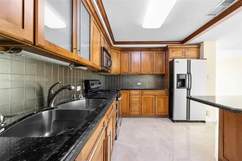 a kitchen with stainless steel appliances granite countertop a sink and a refrigerator