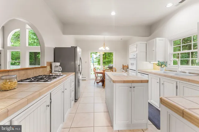 a kitchen with a stove a refrigerator a sink dishwasher with a dining table and chairs