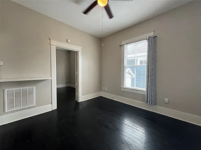 an empty room with wooden floor chandelier fan and windows