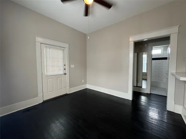 an empty room with wooden floor cabinet and windows