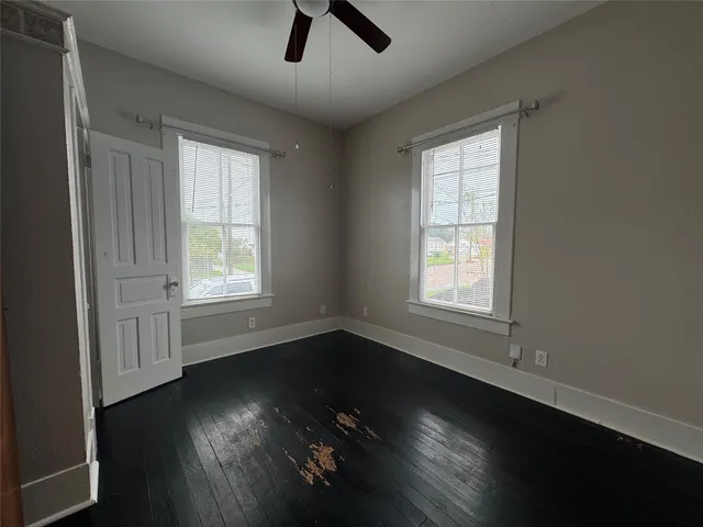 an empty room with wooden floor and windows