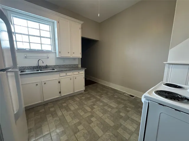 a room with a stove a sink and a window