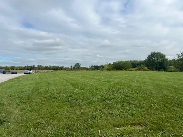 a view of a field with an ocean and trees in the background