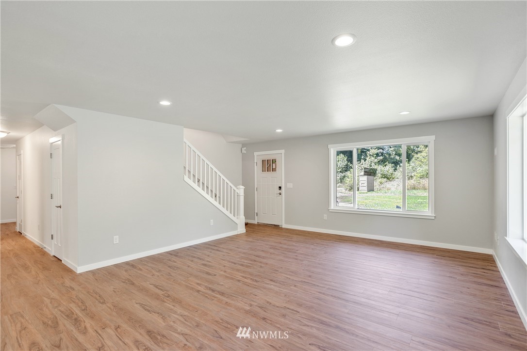 7907 175th Avenue Southwest Rochester, WA 98579 - Photo 11 of 39 an empty room with wooden floor and windows