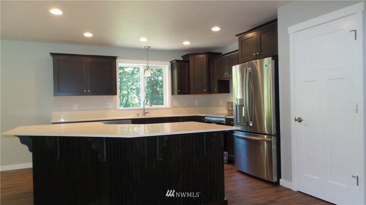 7907 175th Avenue Southwest Rochester, WA 98579 - Photo 18 of 39 a kitchen with stainless steel appliances granite countertop a refrigerator a sink and a stove with wooden floor