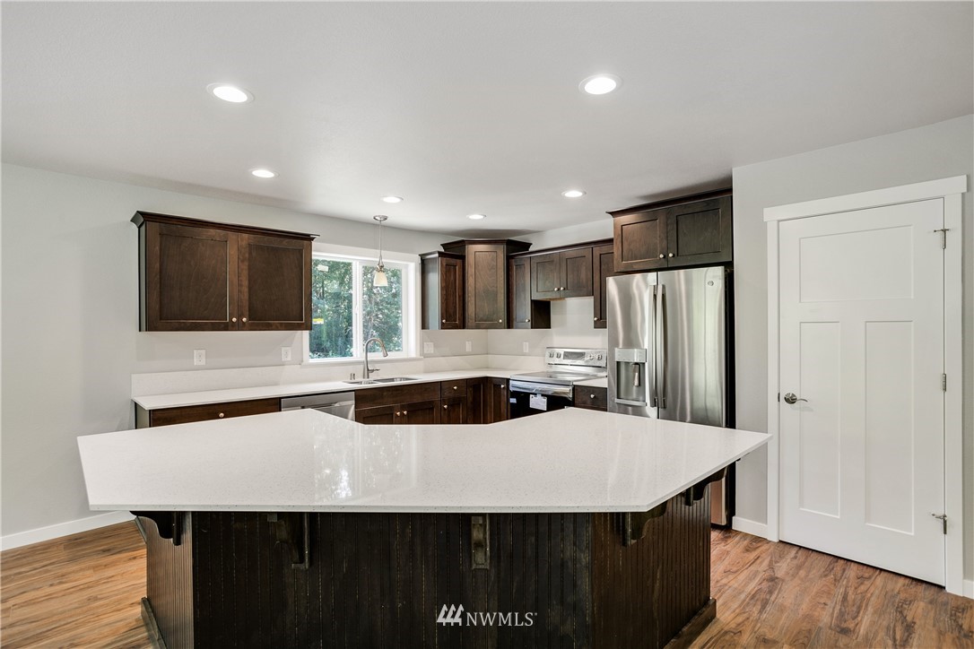 7907 175th Avenue Southwest Rochester, WA 98579 - Photo 21 of 39 a kitchen with stainless steel appliances granite countertop a sink a microwave a refrigerator and white cabinets