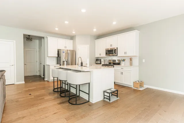 a kitchen with white cabinets and chairs