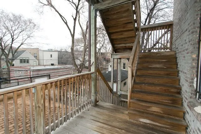 a view of a balcony with wooden floor and fence and a bench