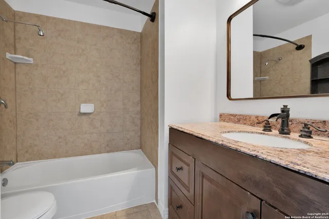 a bathroom with a granite countertop bathtub sink vanity mirror and toilet
