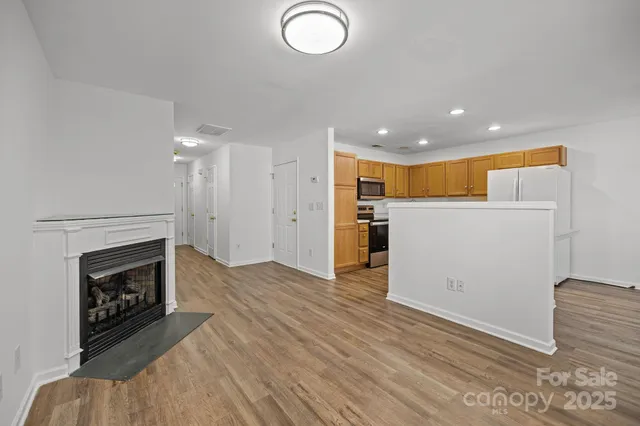 an empty room with wooden floor fireplace and windows