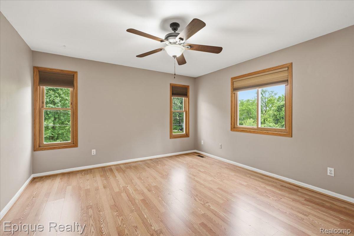 1221 Rhodes Road Lake Orion, MI 48360 - Photo 36 of 72 Spacious room featuring wood-finish flooring, light tan wall paint, and multiple windows with natural wood trim