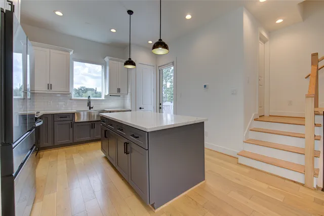 a large kitchen with a large center island wooden floor and stainless steel appliances