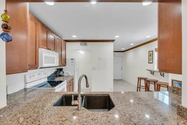 a kitchen with stainless steel appliances granite countertop a sink a stove and a refrigerator
