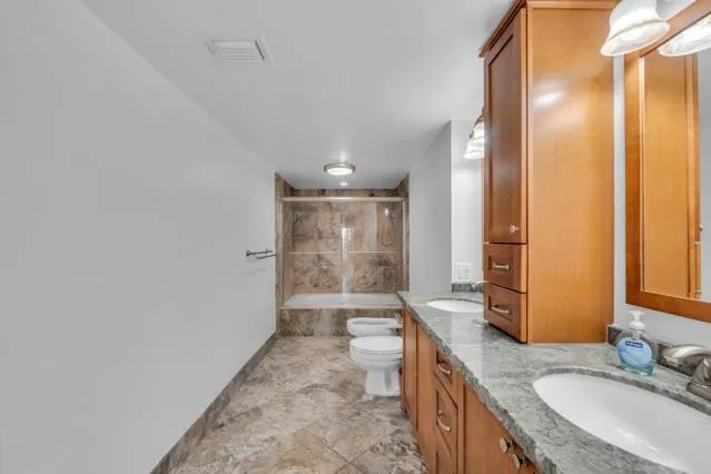 a bathroom with a granite countertop sink toilet mirror and shower
