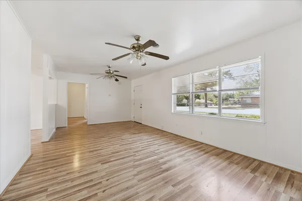 a view of an empty room with a window and wooden floor