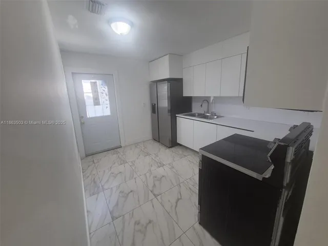 a kitchen with a refrigerator and a stove top oven