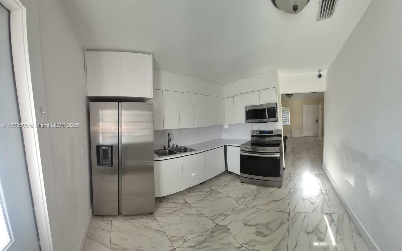 7756 Washington Avenue, Unit 7758 Lake Worth, FL 33462 - Photo 5 of 15 a large kitchen with cabinets and stainless steel appliances