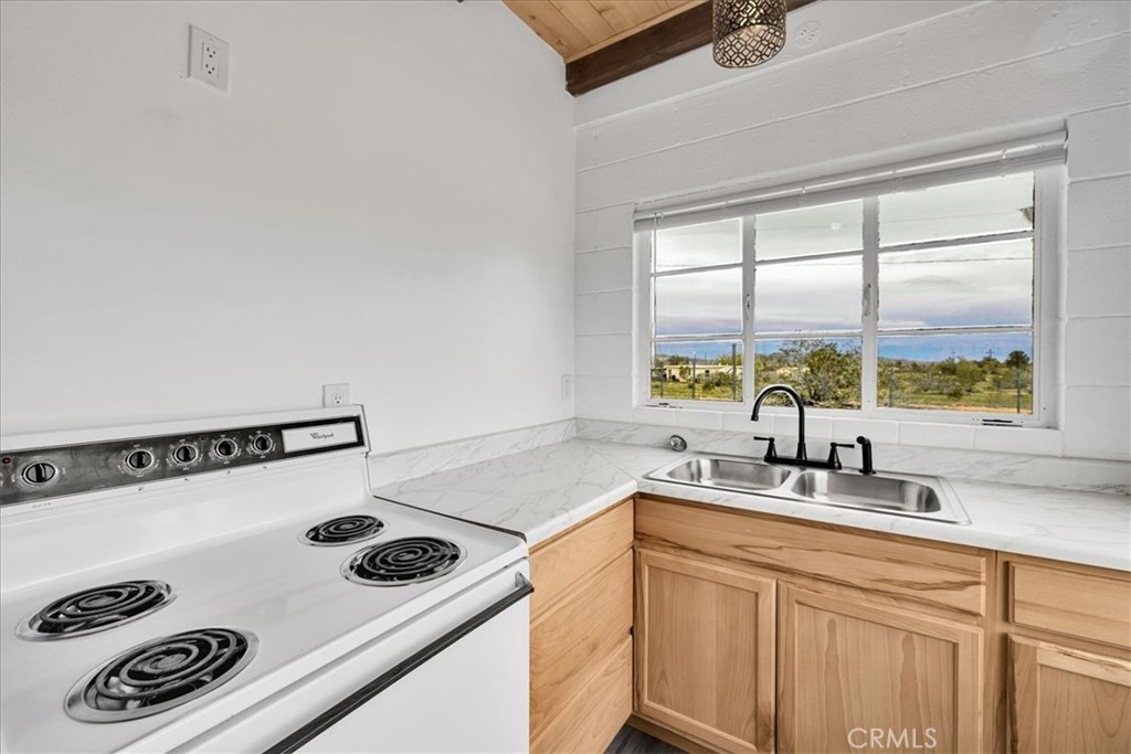 57726 Starlight Mesa Road Yucca Valley, CA 92284 - Photo 10 of 75 a kitchen with a sink a stove and white cabinets