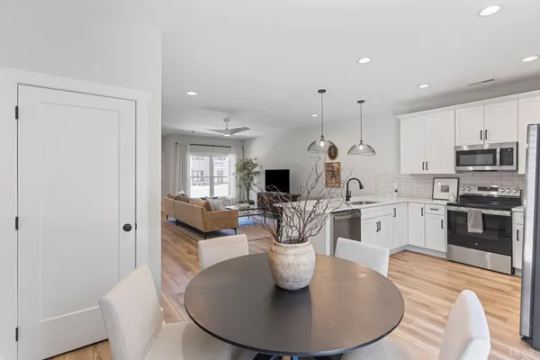 a kitchen with stainless steel appliances kitchen island granite countertop a stove a sink a dining table and chairs