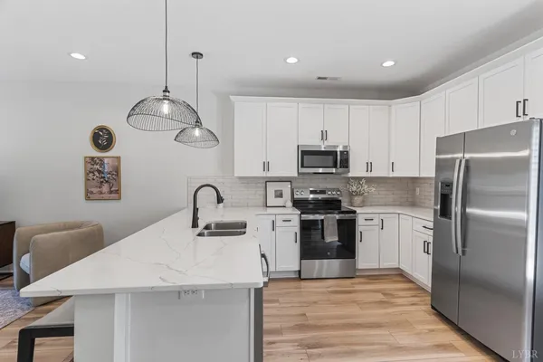 a kitchen with stainless steel appliances granite countertop a sink a stove a refrigerator cabinets and chairs